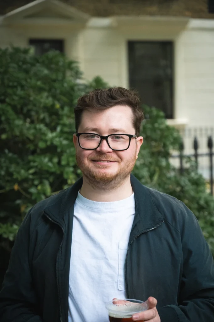 Man with glasses smiling in a garden in London